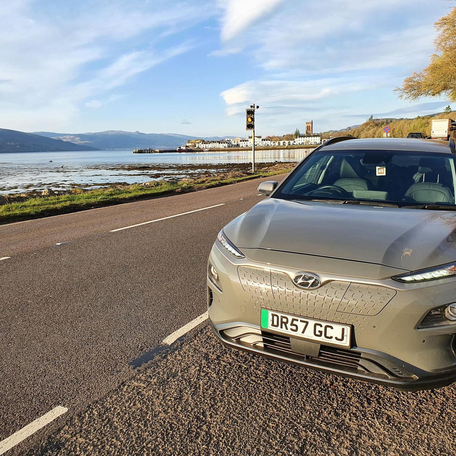image shows electric car hyundai next to a lake with hills in the background